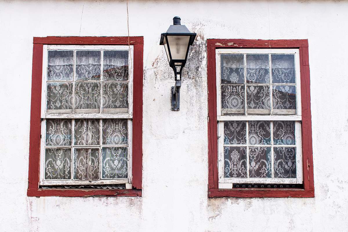 home decor turned-off sconce lamp between two windows curtain